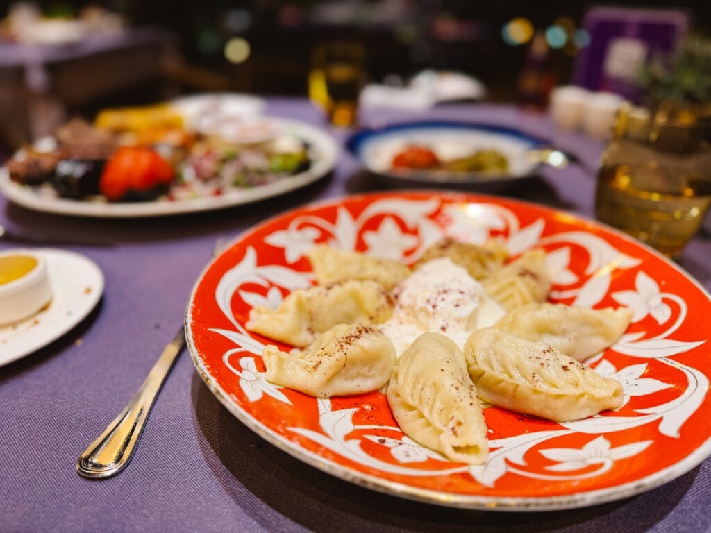 Gurze dumplings topped with sumac with yogurt in the center on a red and white Azerbaijani plate