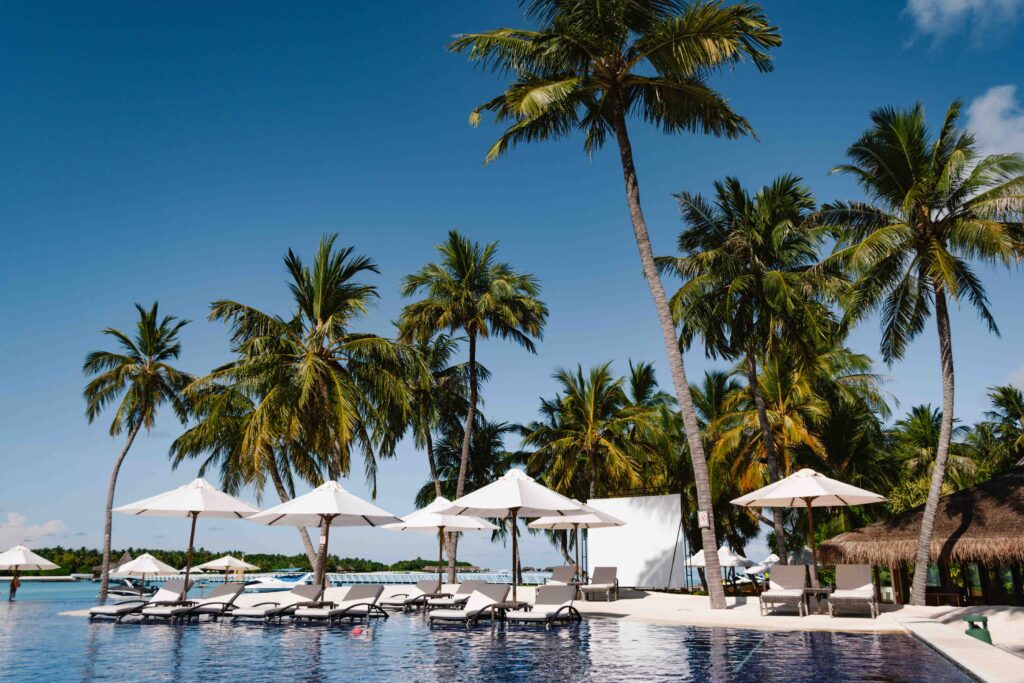 View of The Main Pool at Conrad Maldives with palm trees in the background