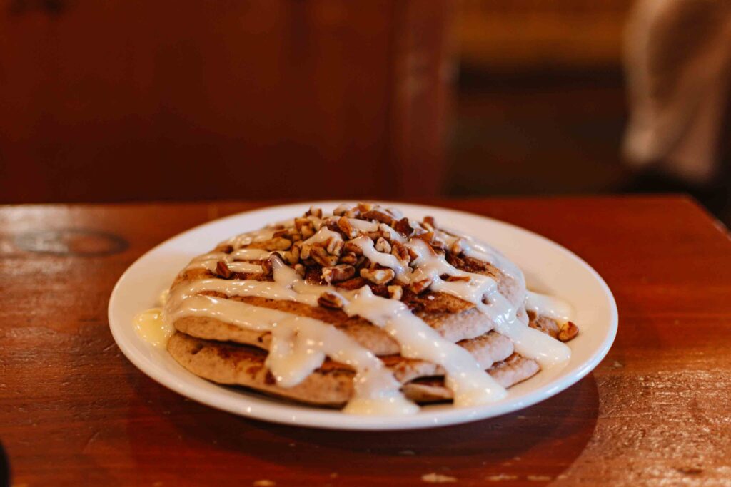 Stack of pancakes with icing and pecans on top on a wood table at Flapjacks Pancake Cabin in Gatlinburg, the pancake capital of the South
