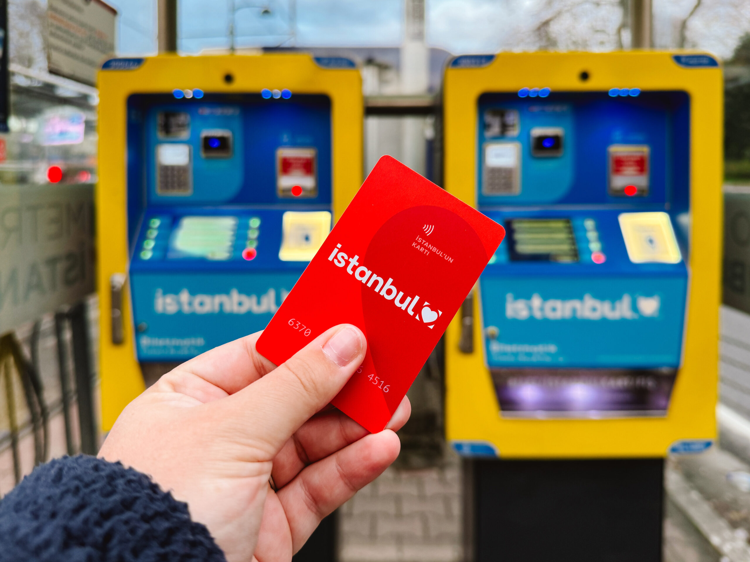 Woman's outstretched hand holding red Istanbulkart, a public transportation card used in Istanbul to get around the city.