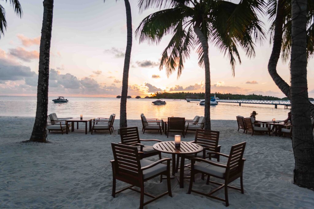 View of sunset on the water from the beach restaurant with tables in the sand