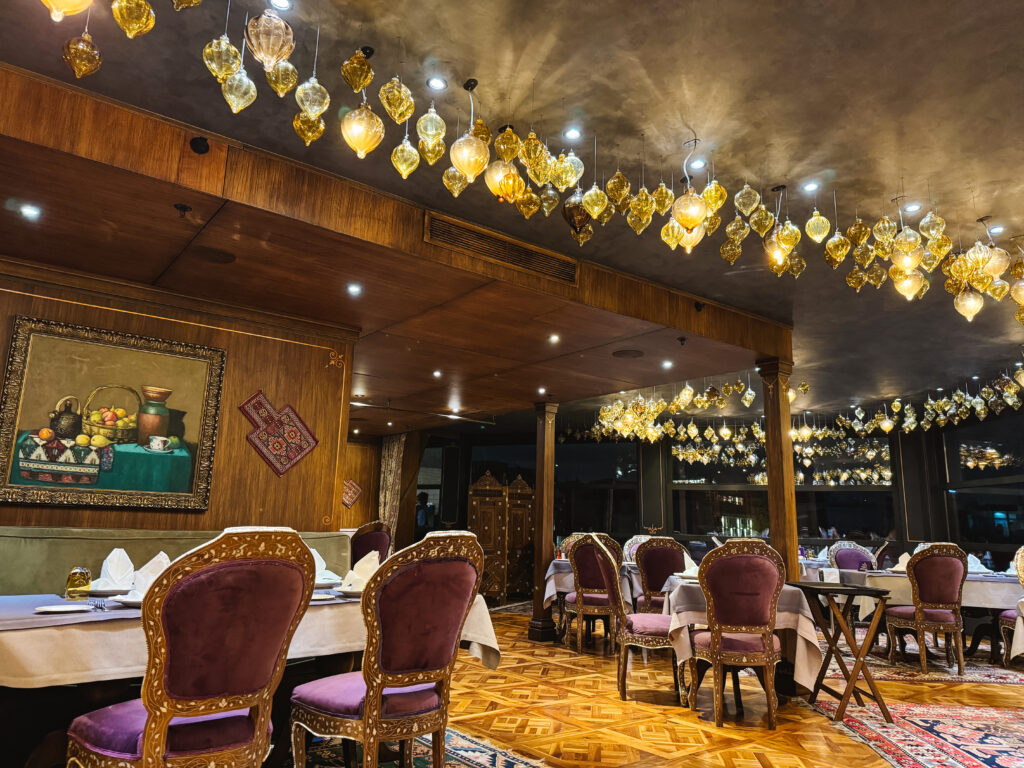 Interior of rooftop indoor restaurant in Istanbul with purple decor and yellow glass lamps