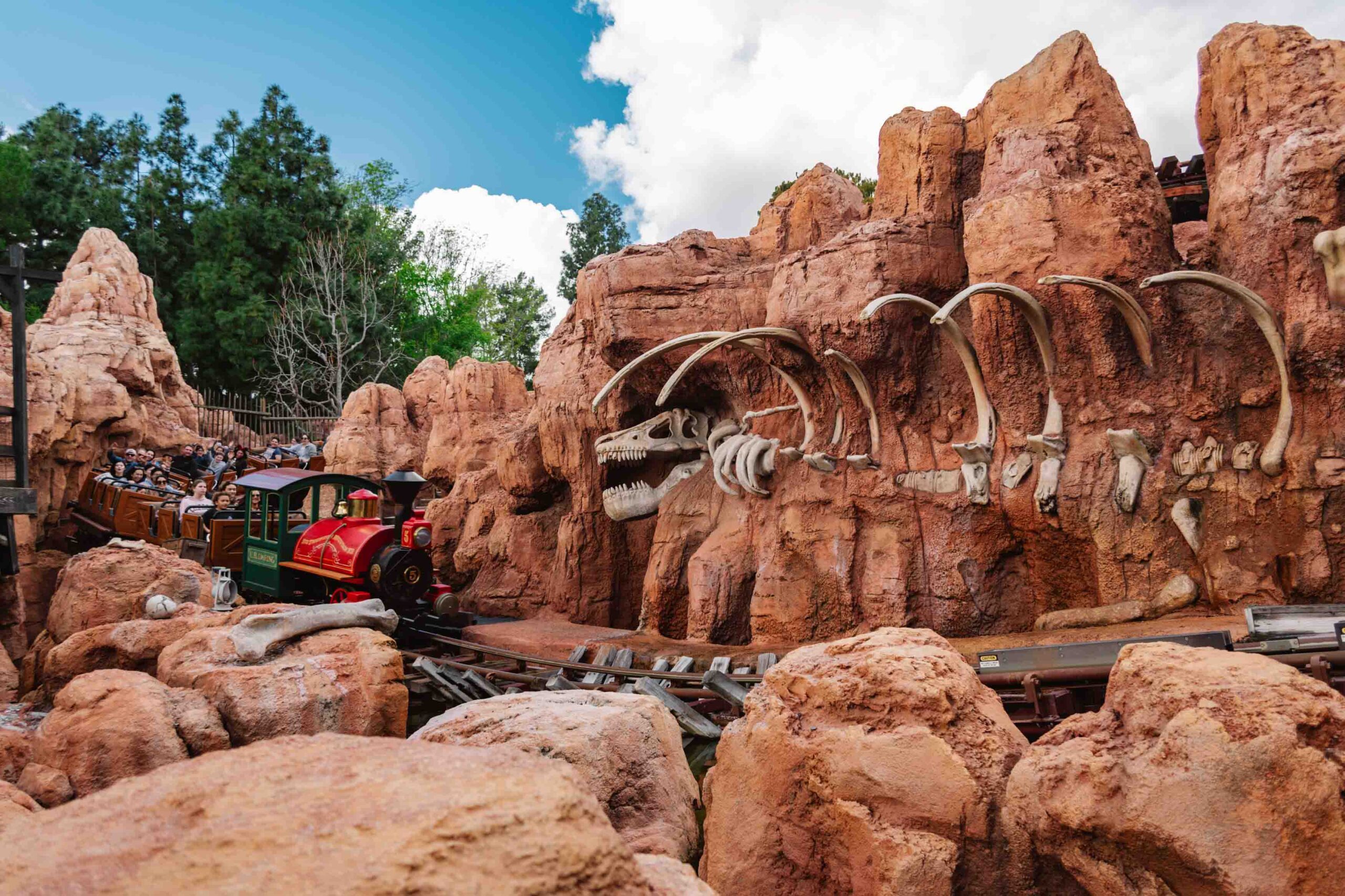 Train roller coaster passing red rock decor and fake fossils as part of Disney's Big Thunder Mountain, an essential ride even if you only have one day in Disneyland