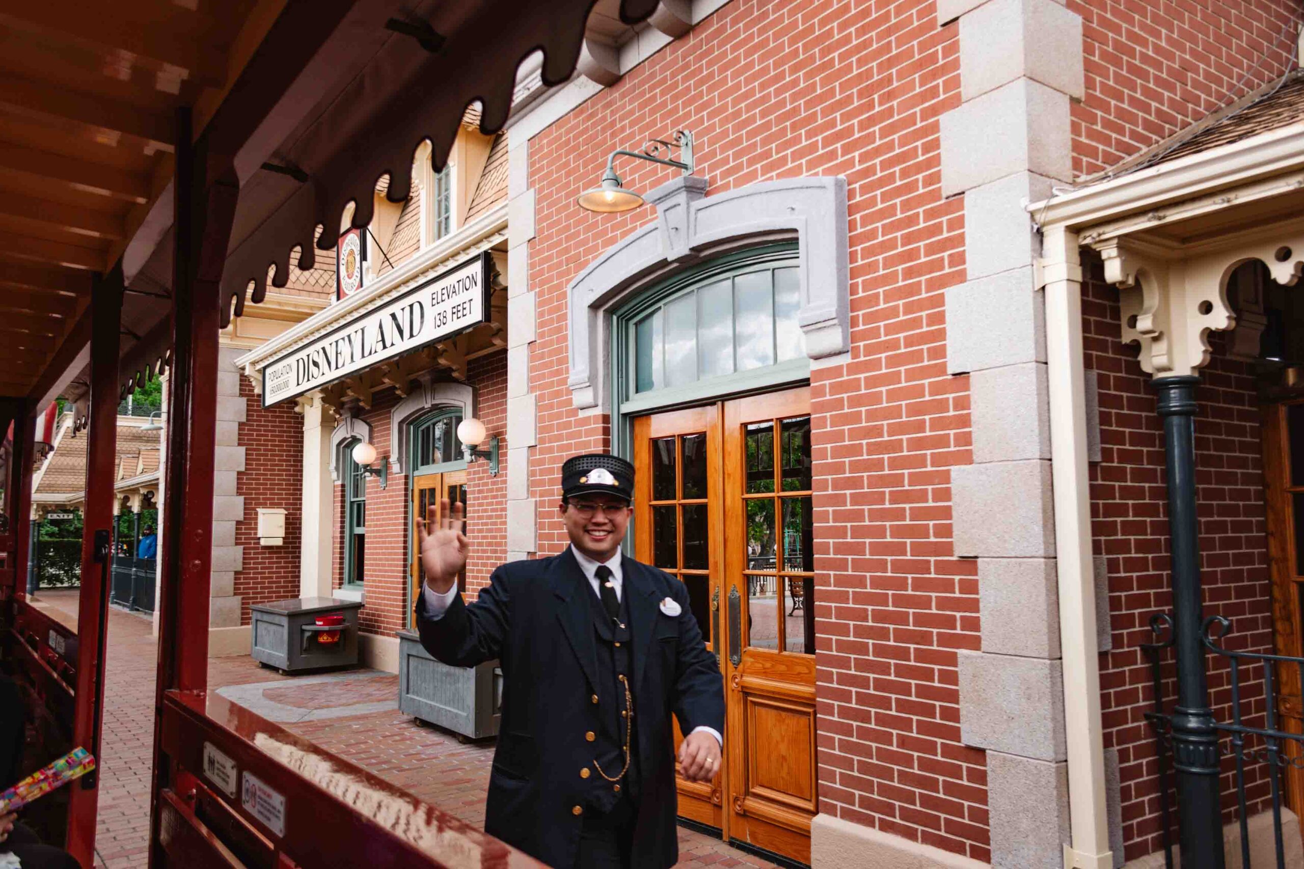 Disneyland Railroad conductor waving at train riders coming through to Main Street Station