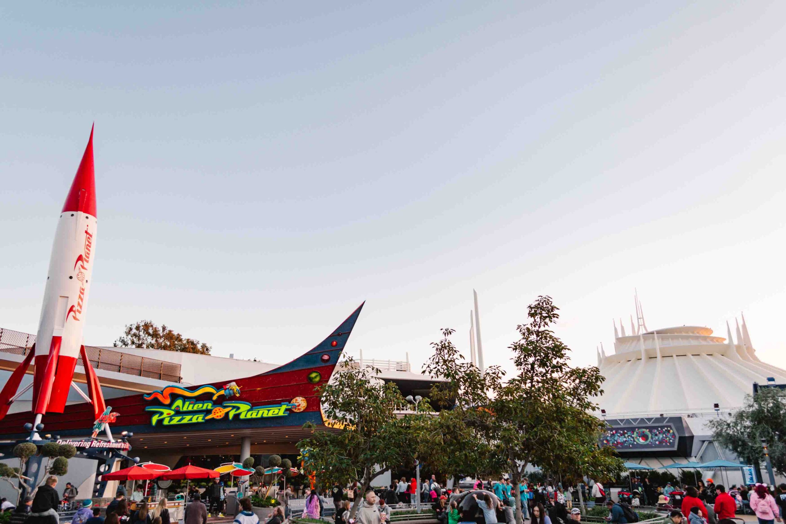 View of Pizza Planet and Space Mountain in Tomorrowland at Disneyland during sunset, one of the best sections of the park