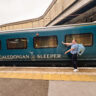 Woman pointing to the Caledonian Sleeper label on the outside of the overnight train car