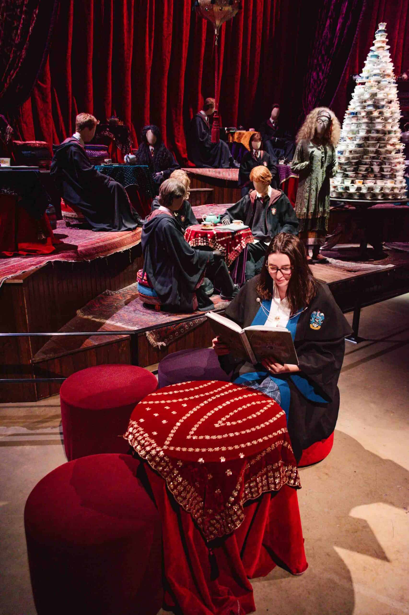 Woman sitting in Hogwarts apparel in the Divination Classroom set at the Warner Brothers Studio Tour in London