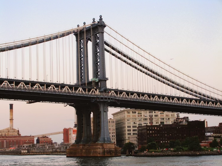 Side view of the Brooklyn Bridge at sunset with Brooklyn in the background