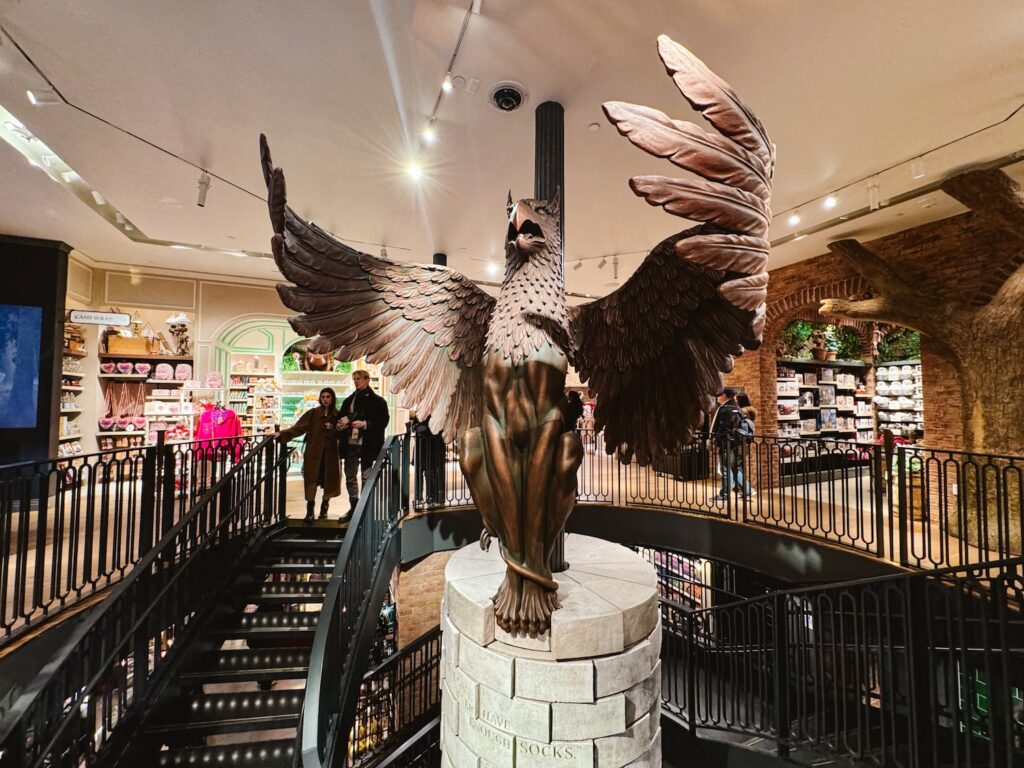 Hippogriff statue with wings extended in the center of the large spiral staircase in the Harry Potter New York Store