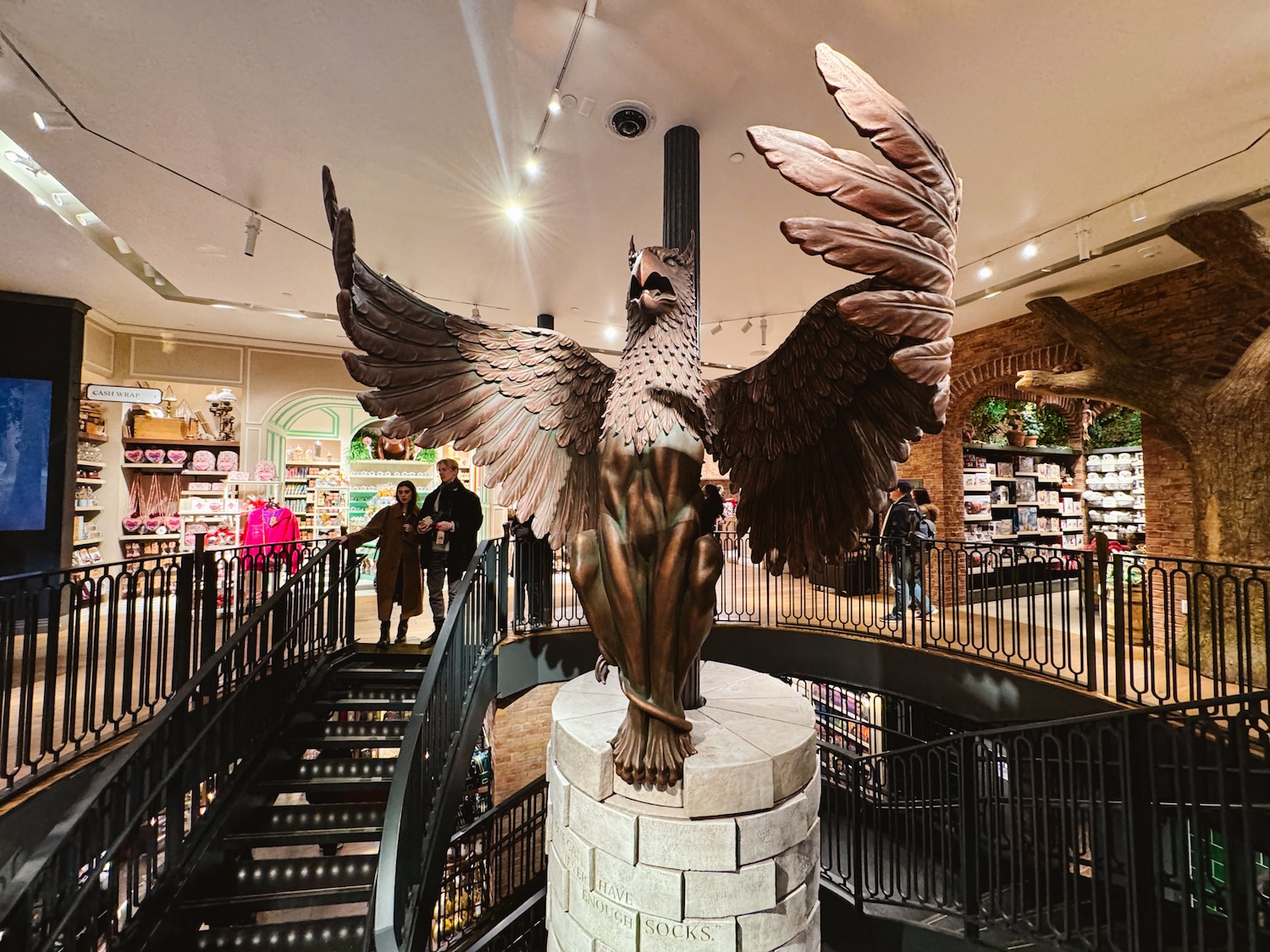 Hippogriff statue with wings extended in the center of the large spiral staircase in the Harry Potter New York Store