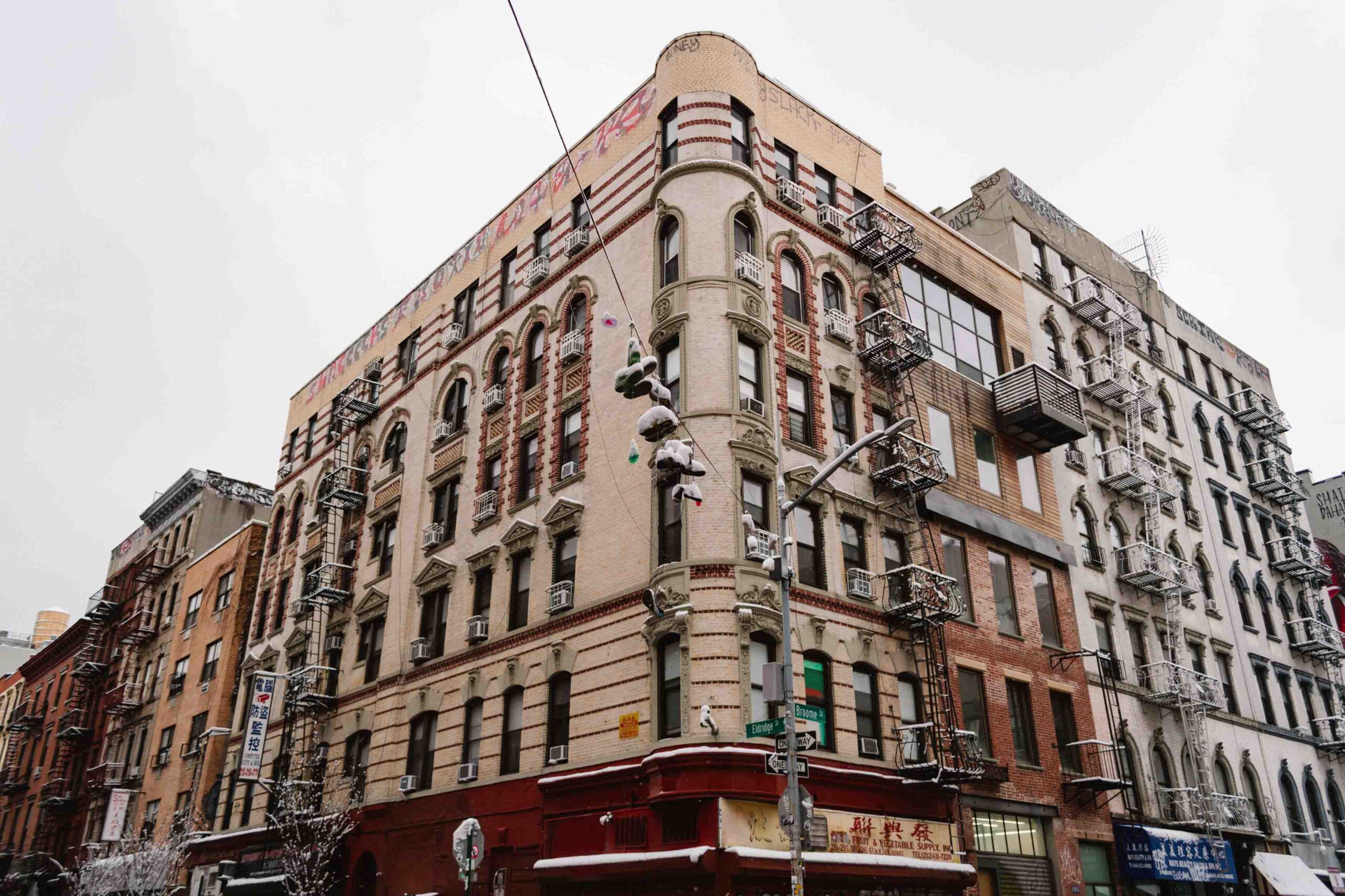 Winter cityscape of a New York building with shoes on telephone wires covered in snow.