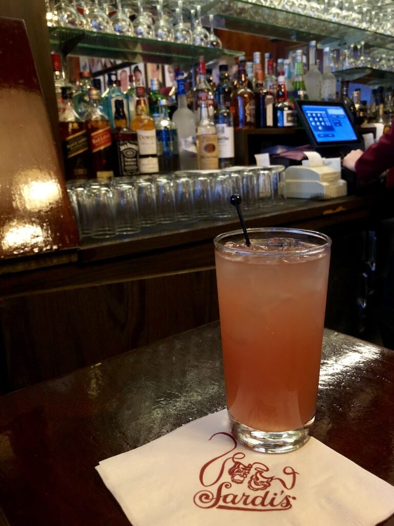 One of the best places to eat near Broadway is Sardi's, one of the most iconic spots with a bar where a cocktail at the bar is pictured here on a Sardi's branded napkin