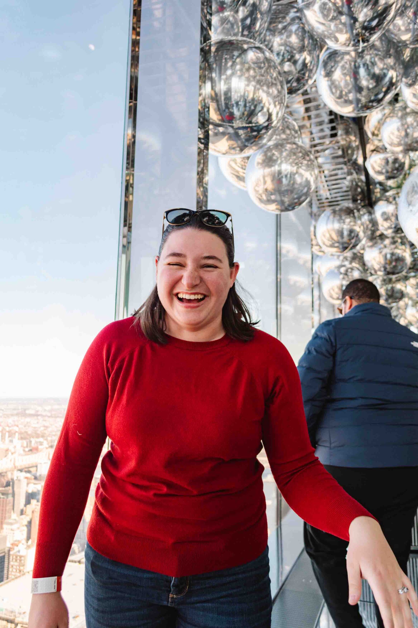 Woman laughing while in a high rise art installation in New York with reflective silver balloons floating around