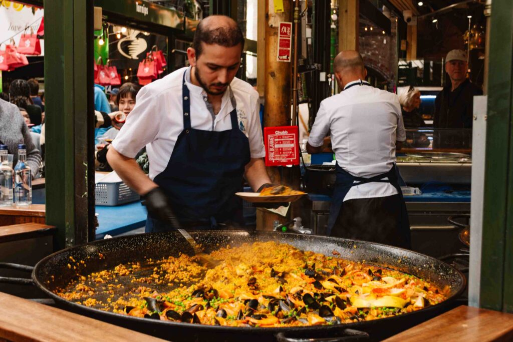 Man stirring a huge pot of paella in Borough market