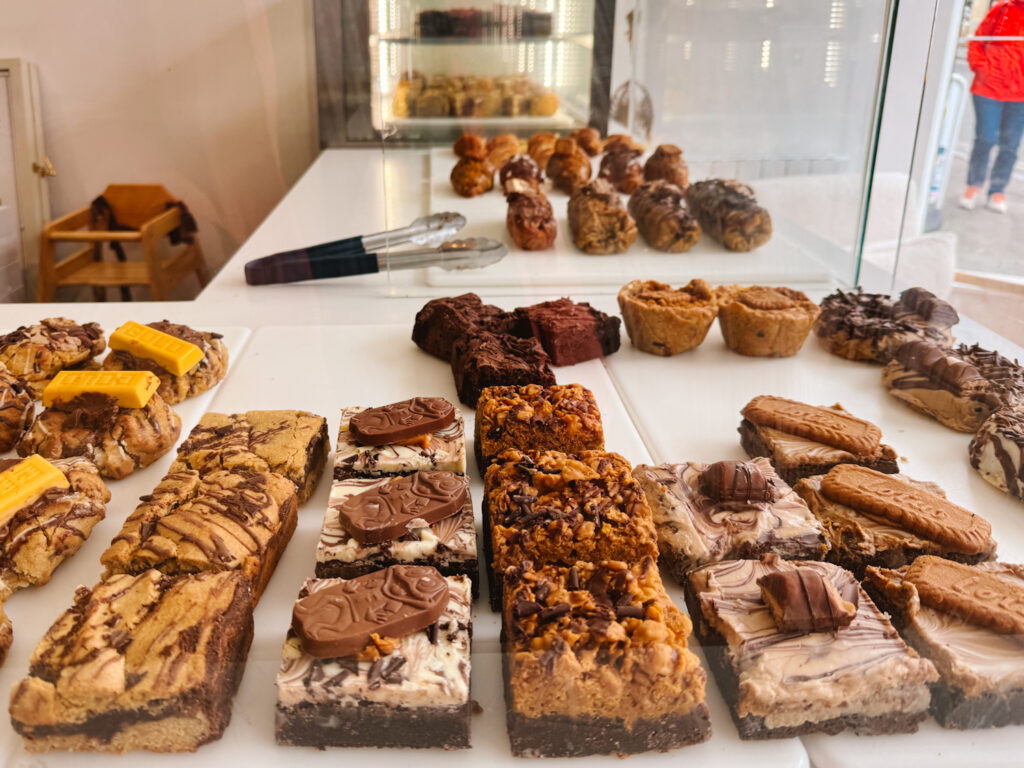 View looking into a bakery display case with various types of brownies and bars