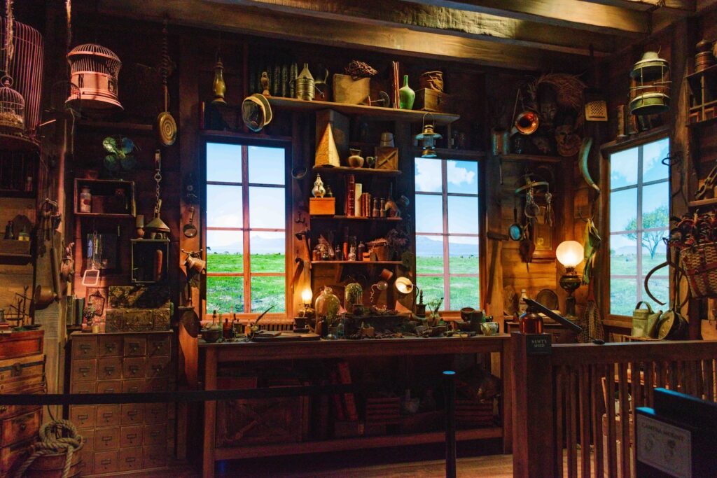Inside Newt Scamander's trunk set with kitchen and creatures passing on screens for the windows