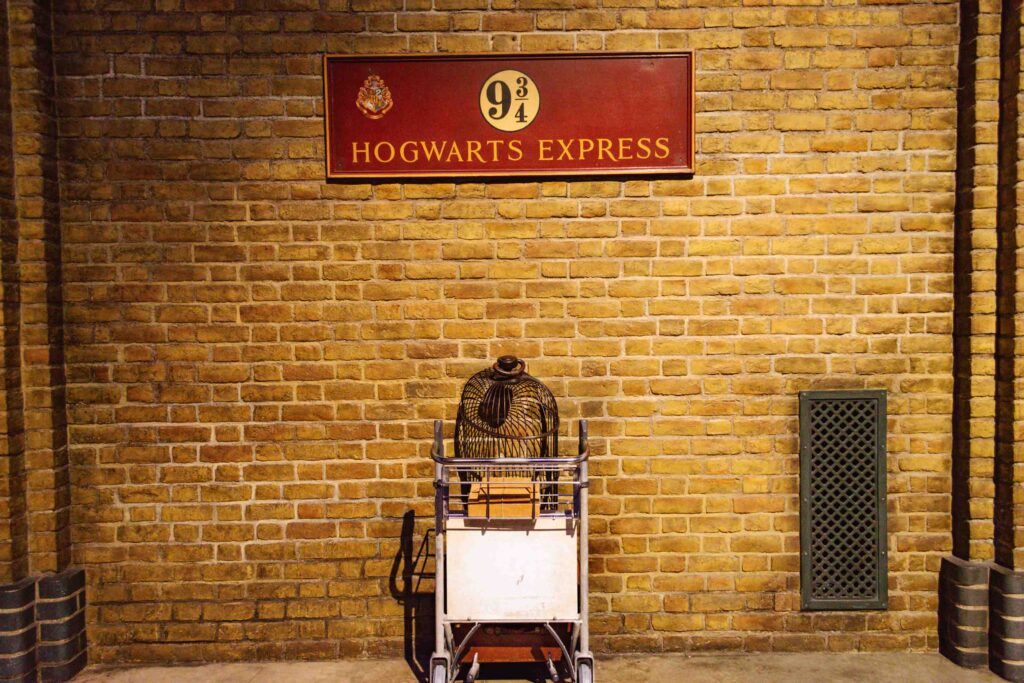 View of Platform 9 ¾ transition in progress with luggage cart halfway through the wall