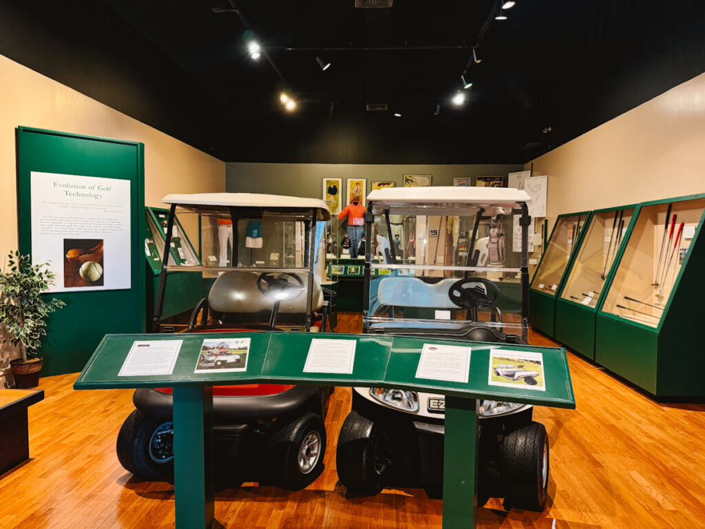 Golf exhibit in Augusta History Museum with two green golf carts on display
