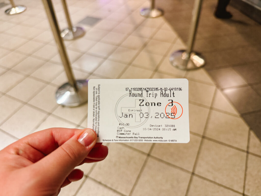 Woman holding a roundtrip ticket to Salem from Boston for October trip