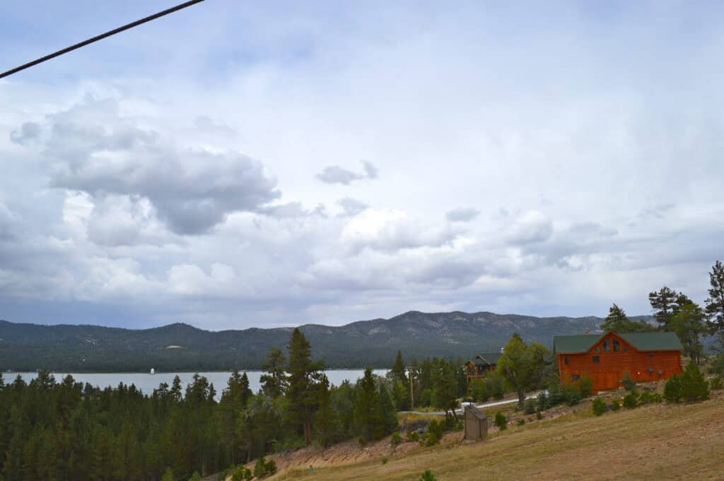 Side view from a chair lift in summer of a lone cabin on the side of a lake mountain, one of the best places to stay in Big Bear
