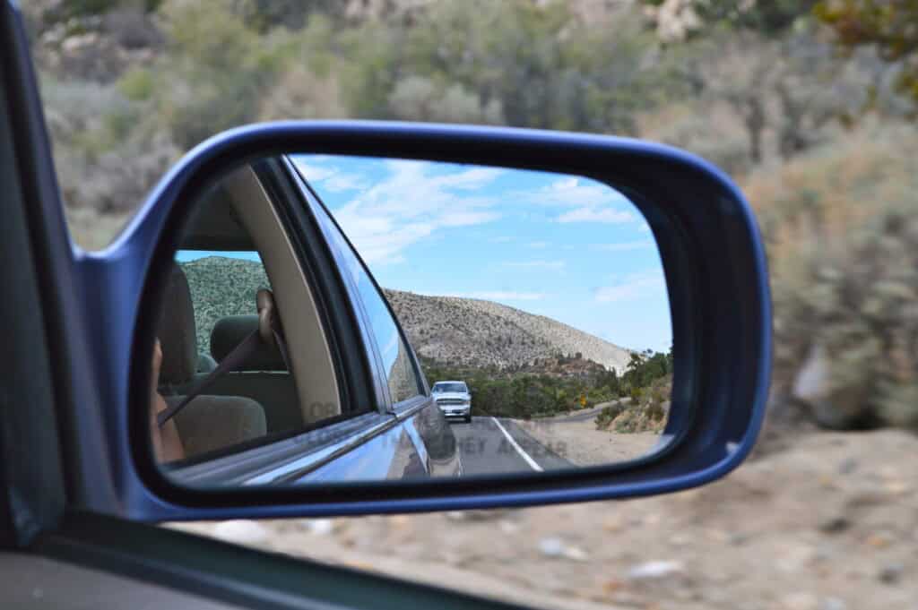 California road trip view in the side mirror of a car on the passenger side showing the desert behind