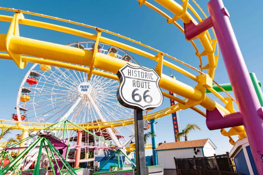 Route 66 sign at Santa Monica Pier with Pacific Park in the background