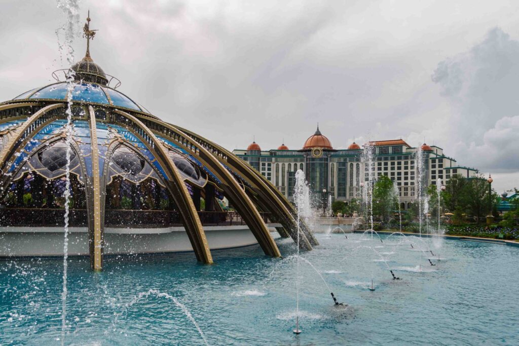 View of Constellation Carousel and surrounding fountain with Helios hotel in the background on a cloudy, rainy day