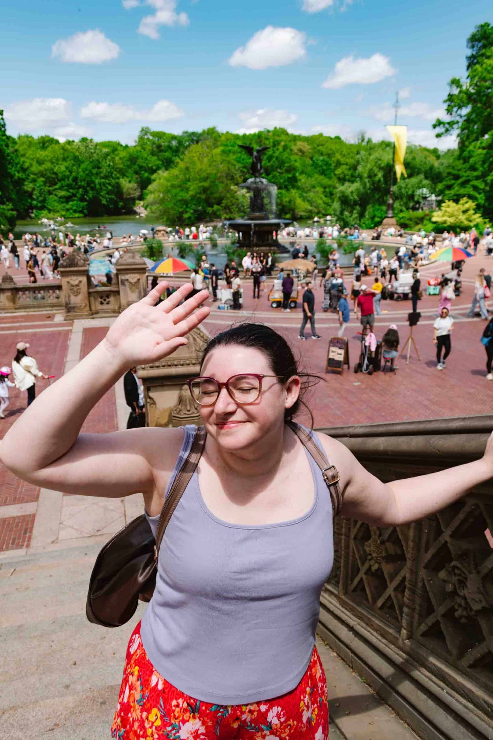 Woman facing the camera and shielding her face from the sun with the Bethesda Terrace