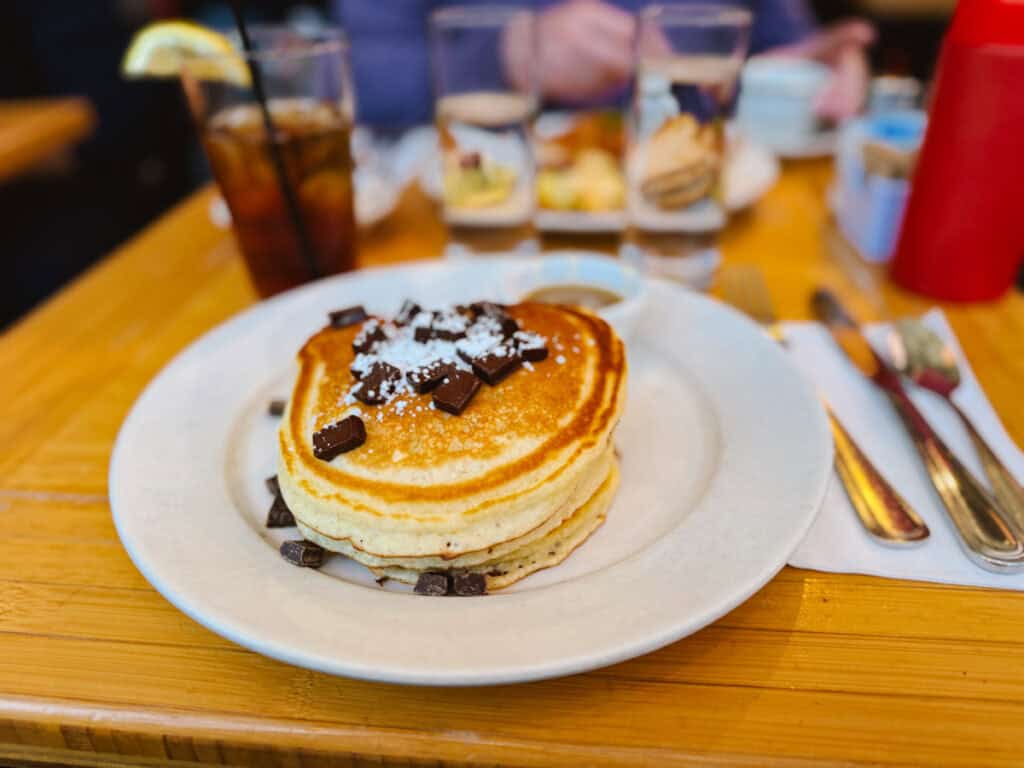 Stack of three puffy pancakes topped with chocolate chunks from Clinton Street Baking Company in New York City