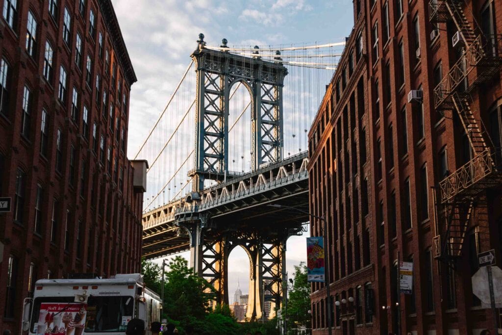 Iconic view of the Brooklyn Bridge with the Empire State Building through the pillars at Water and Washington Streets