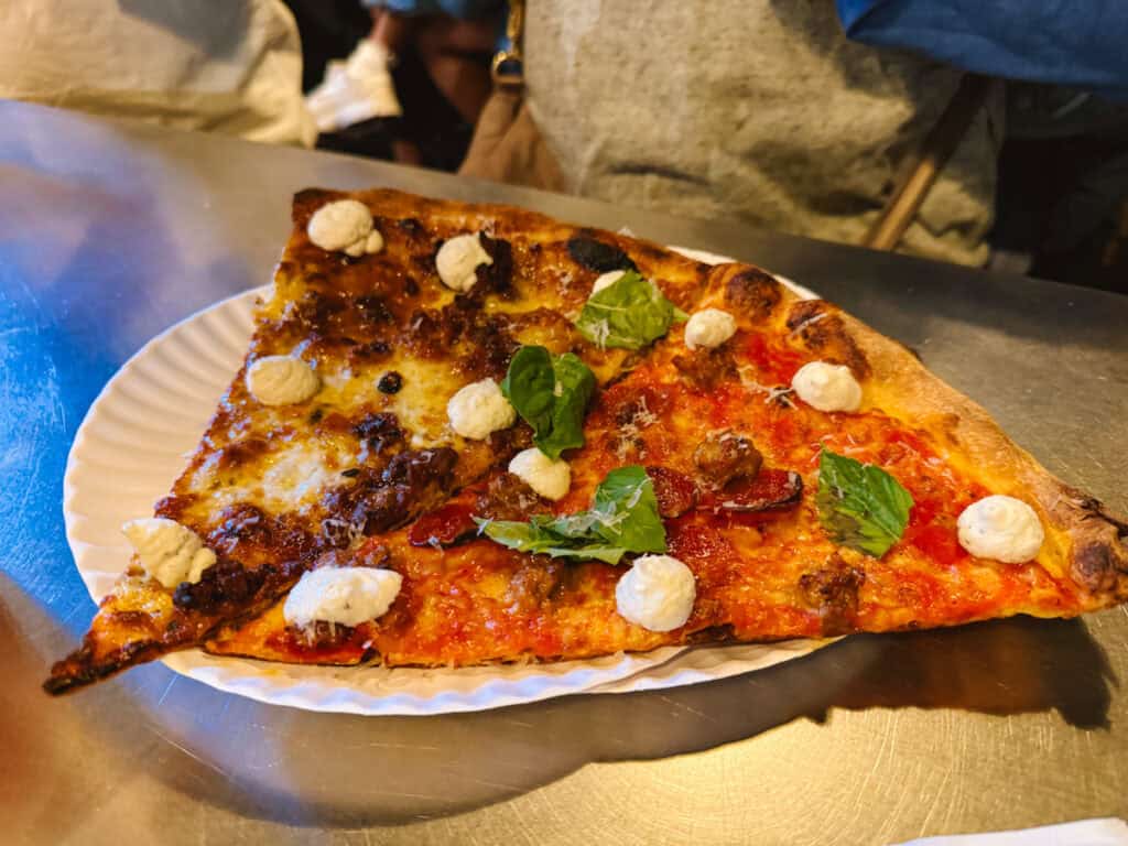Two slices of pizza on a disposable plate, one fig jam and bacon and another that's margherita, from L'Industrie in NYC