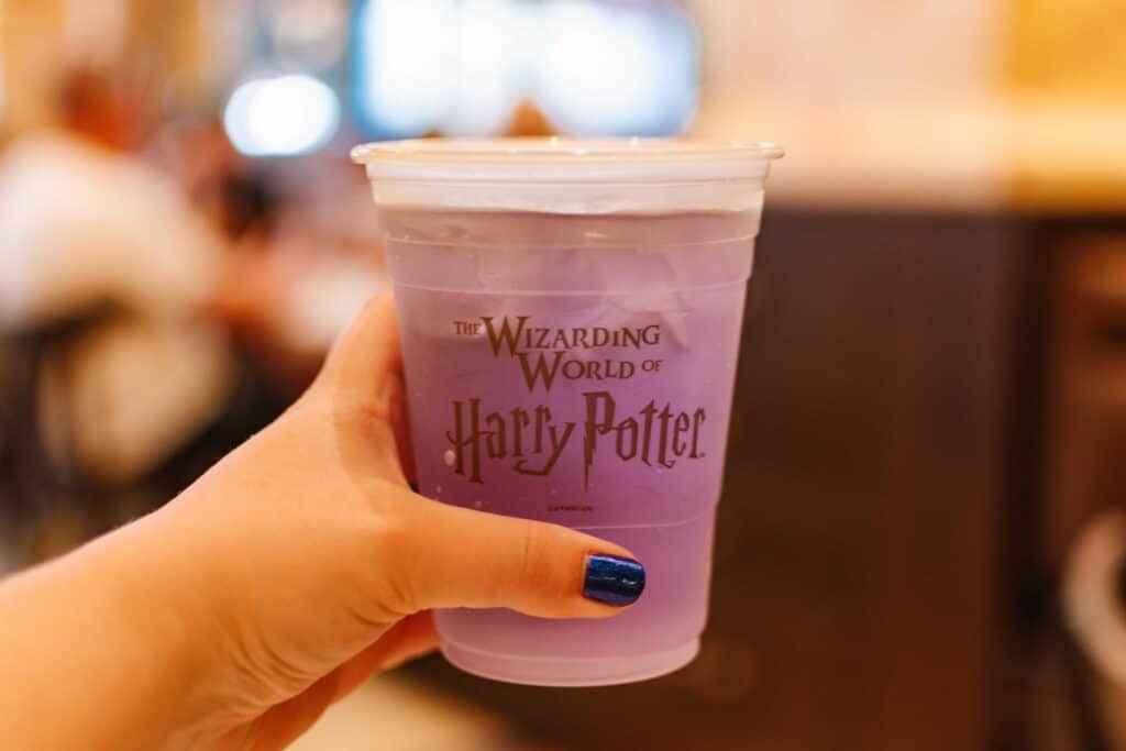 Woman holding a purple lavender lemonade in a Wizarding World of Harry Potter branded plastic cup