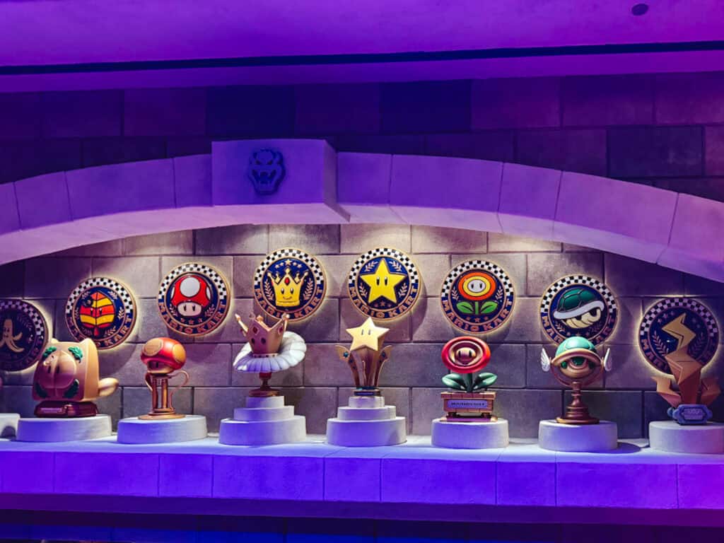 View of the different cups known from Mario Kart with live action statues displayed in the ride queue for Mario Kart: Bowser's Challenge