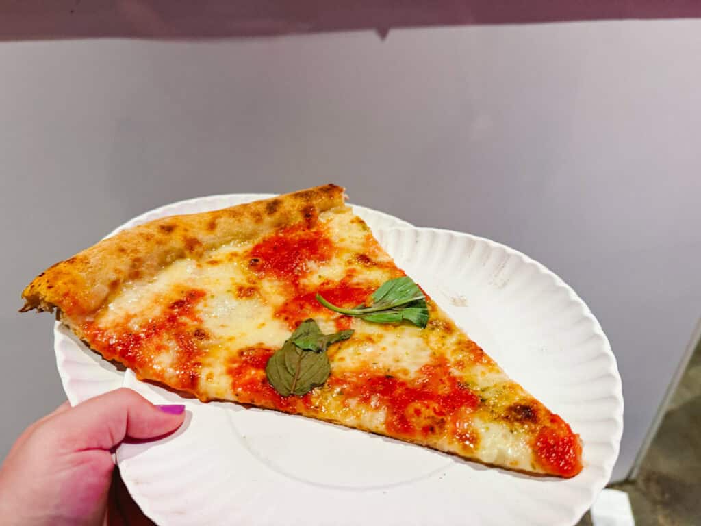 Black-owned pizza spots in New York include Scarr's Pizza, where a margherita slice is shown here on a disposable plate