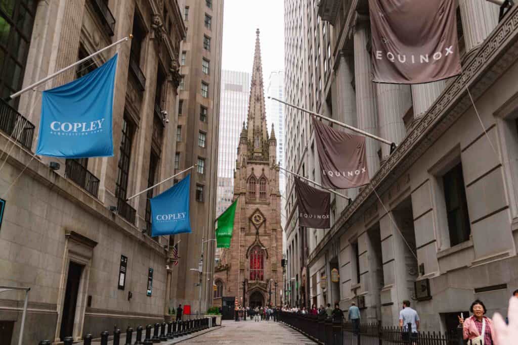 View of Trinity Church between two Wall Street buildings