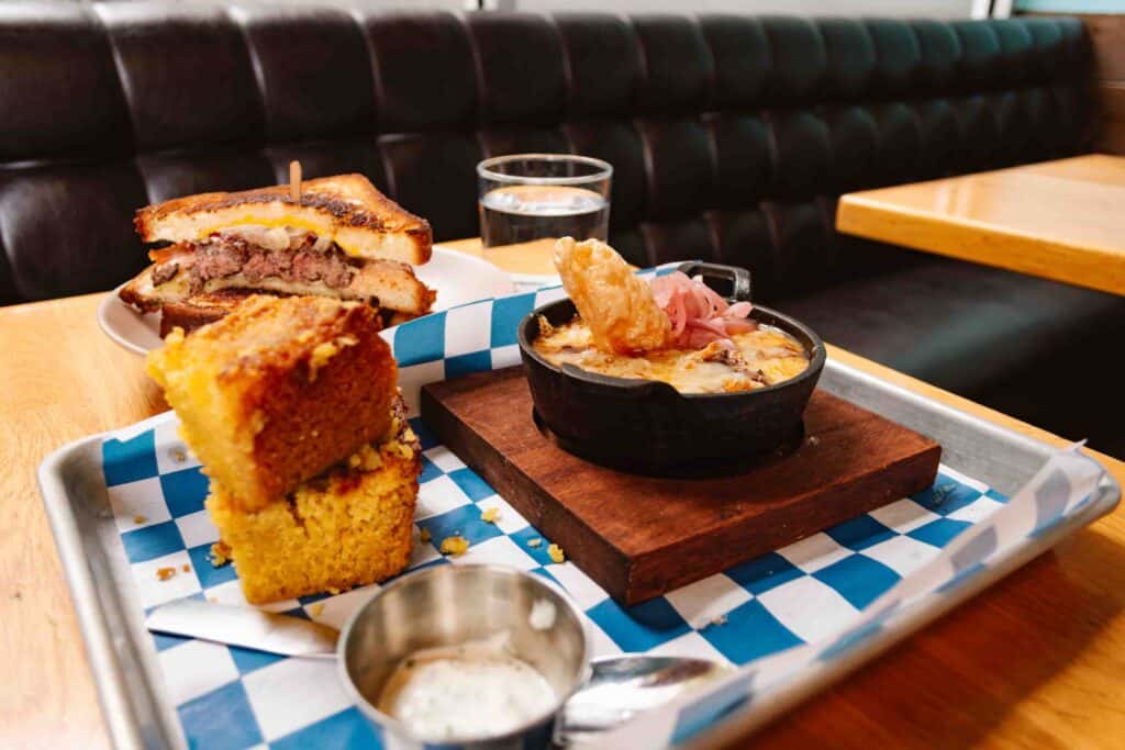 Chili and cornbread on a metal tray with blue and white checkered paper