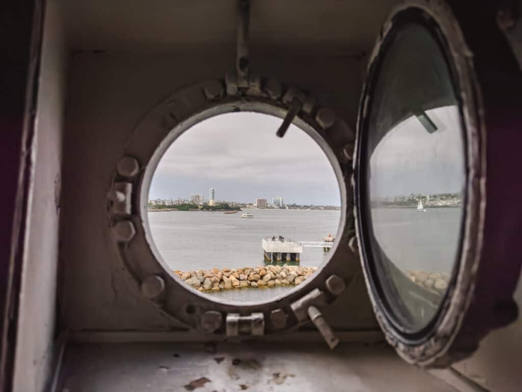 Looking out a porthole at a harbor on a partly cloudy day