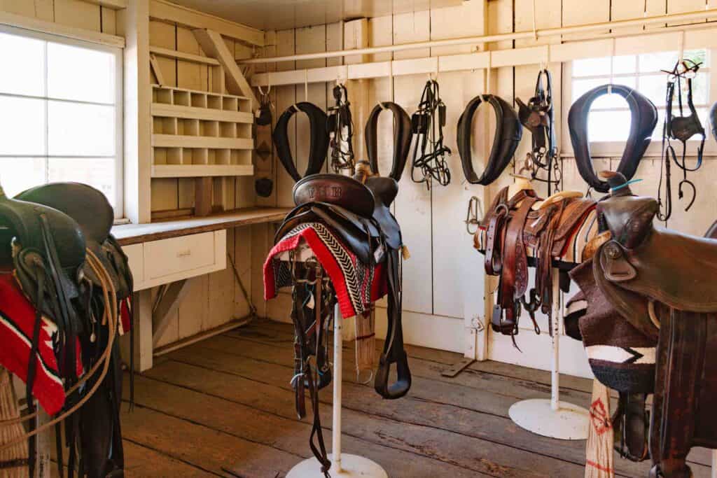 White barn interior with various saddles and horse equipment on a historic rancho