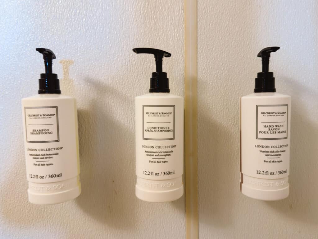 Three refillable bottles of toiletries mounted to a shower wall inside The Queen Mary