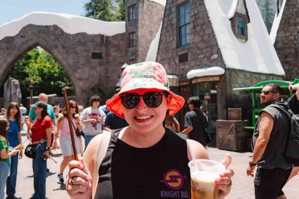 Woman holding a butterbeer and interactive wand inside Hogsmeade at Universal Studios
