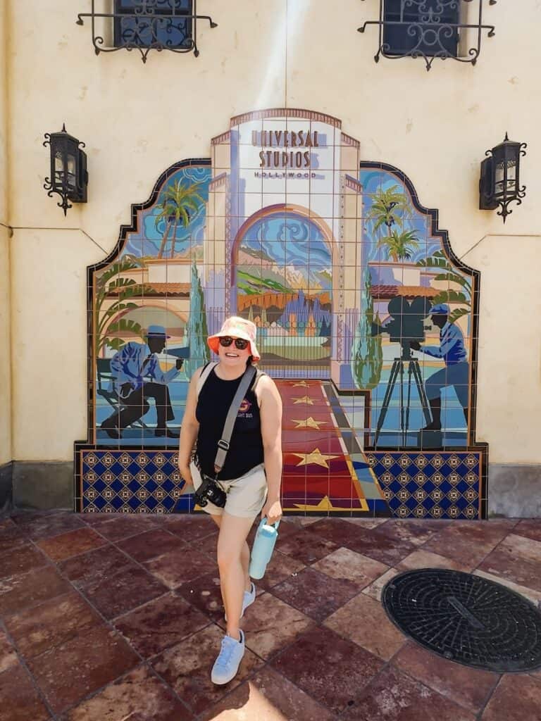 Woman walking toward the camera with a mosaic depicting Universal Studios Hollywood in the background