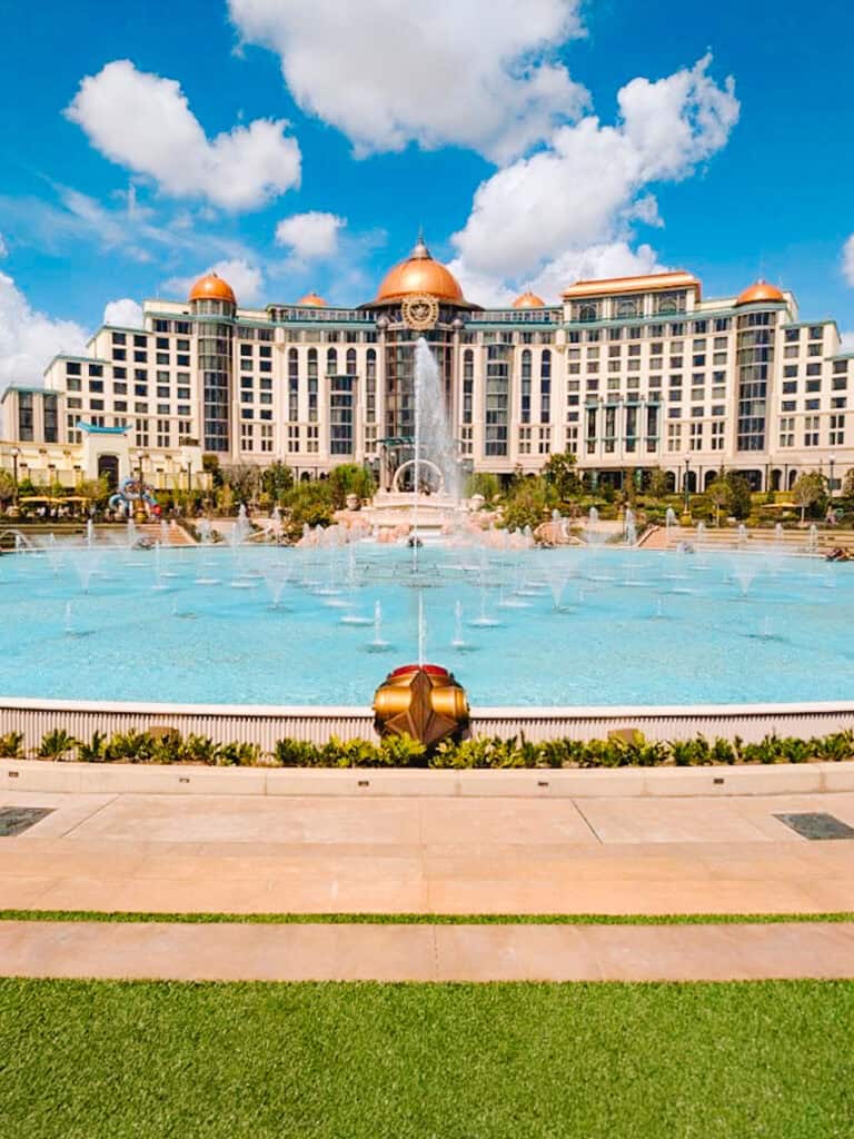 Helios Grand Hotel view from in front of the fountain in Epic Universe on a partly cloudy day