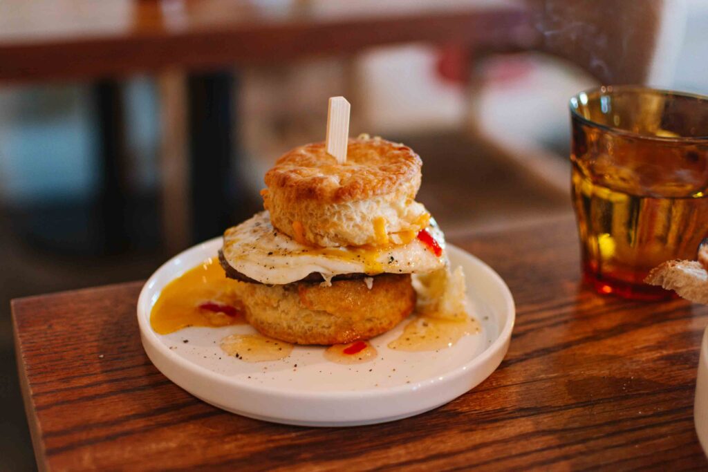 Egg, sausage, and pepper jelly biscuit sandwich on a white plate from a cafe in Columbia TN