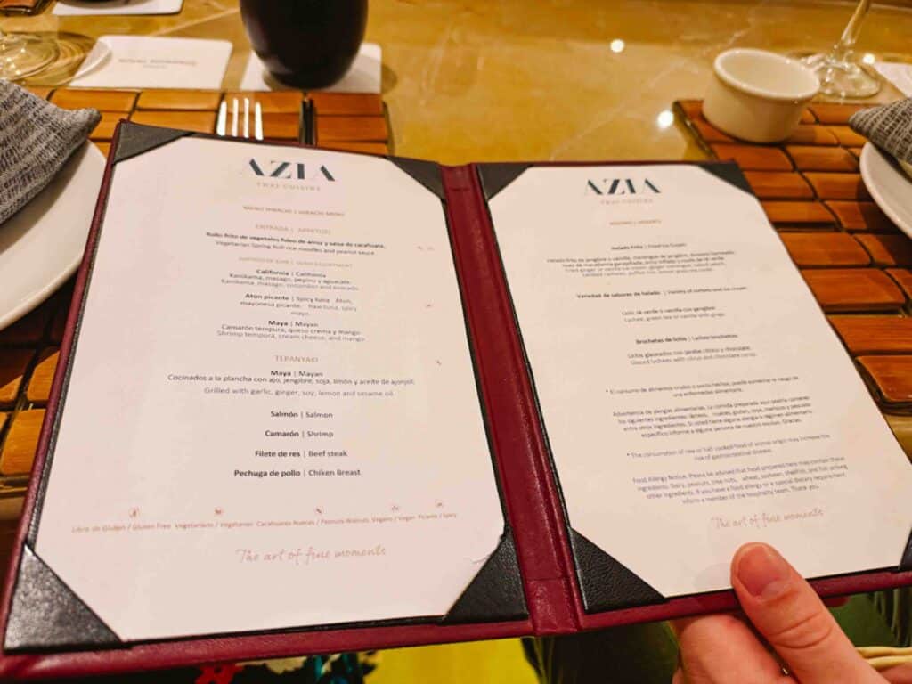 Woman holding an open menu in front of the camera for Azia, a Japanese restaurant in Mexico