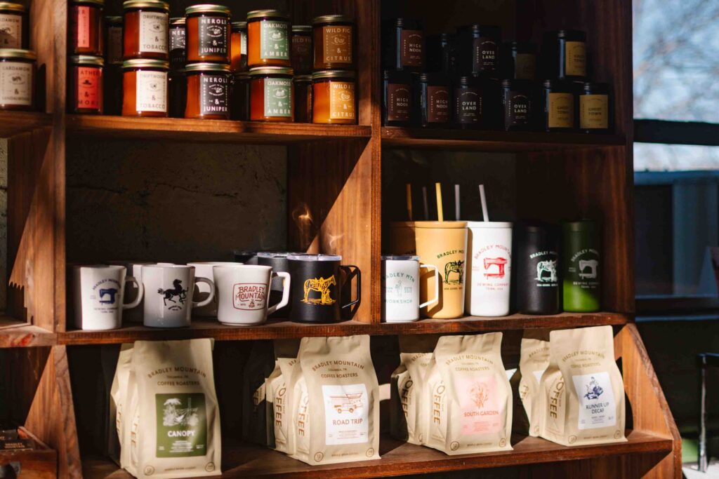 Bradley Mountain coffee for sale with various mugs and tumblers on shelves behind.