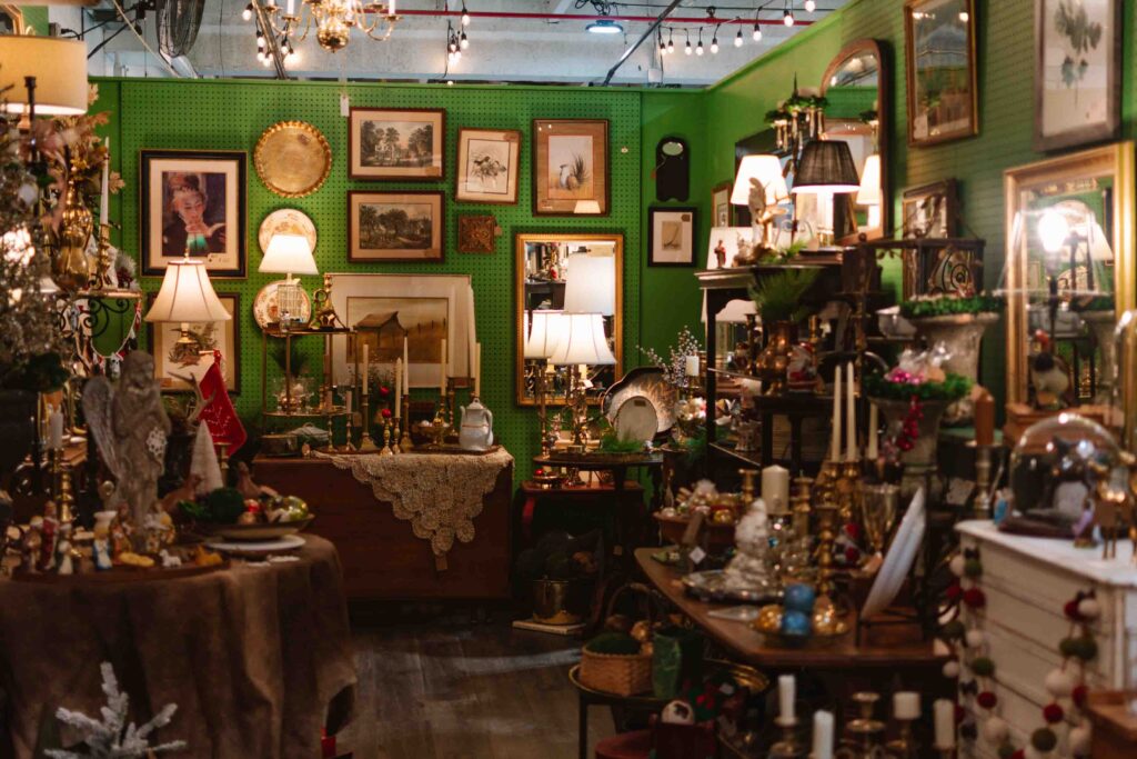 Inside view of an antique market with green walls full of antique furniture, decor, and art