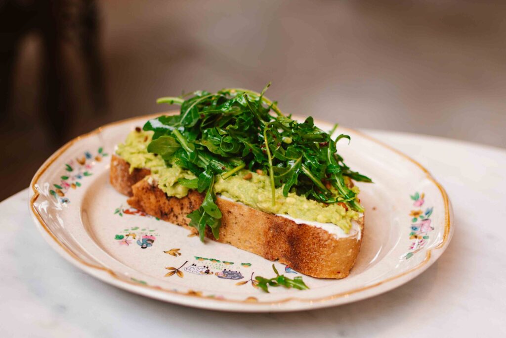 Hank's Coffee Avocado Toast on a vintage Americana plate and topped with arugula