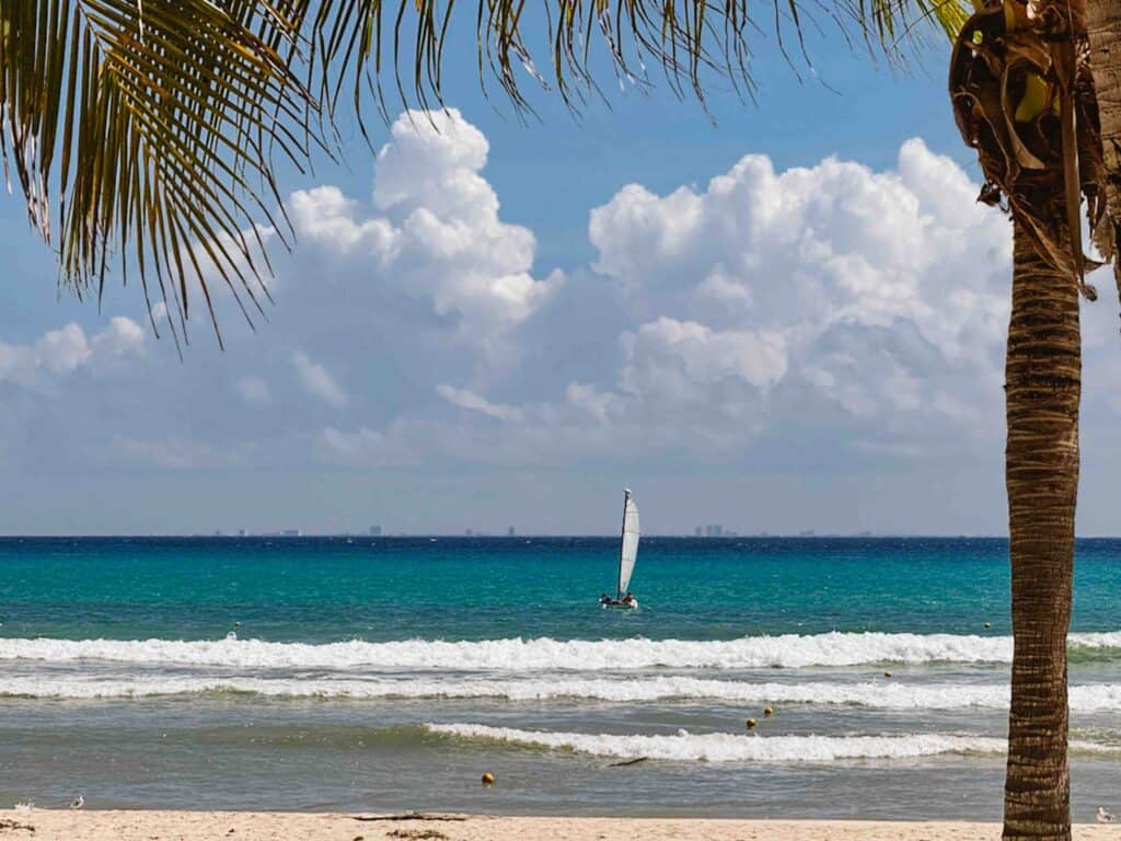 View of the ocean in Playa del Carmen in October with a small windsurfing or sailboat in the distance.
