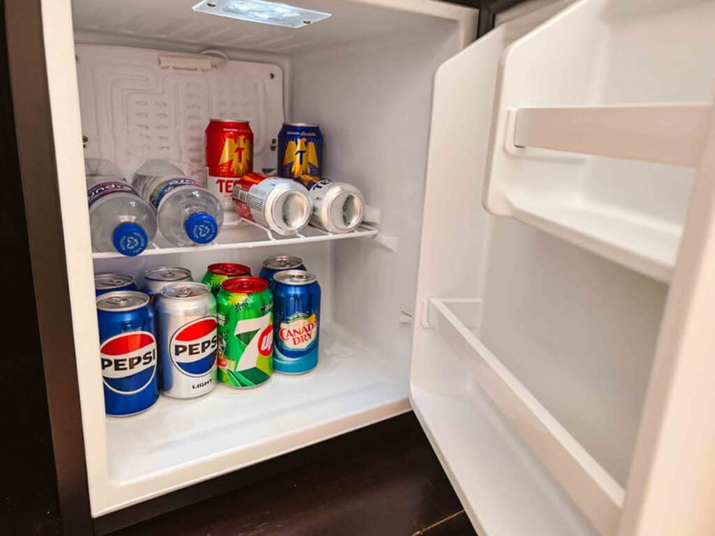 Stocked mini fridge with water, soda, and beer cans in an all inclusive in Playacar, Mexico.