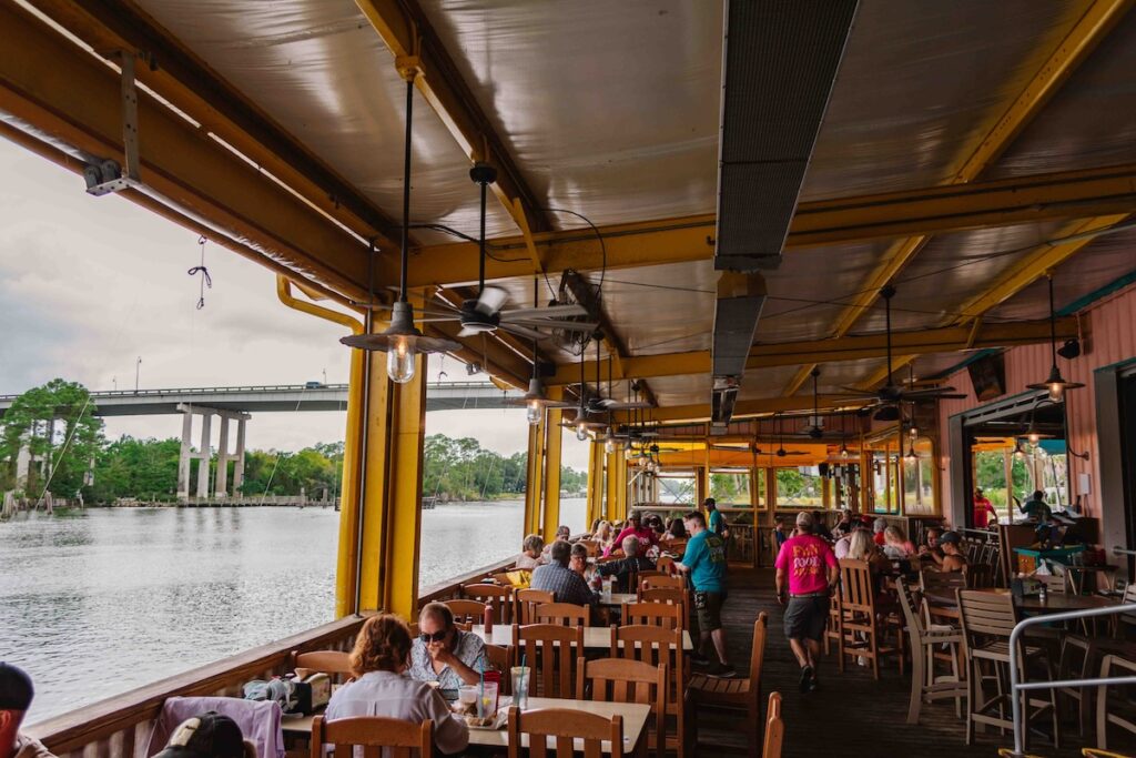 View of an open air restaurant with a waterway to the left and people dining on lunch